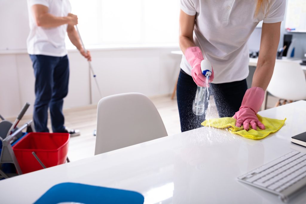 Two Janitor Cleaning The Desk And Mopping Floor In The Office